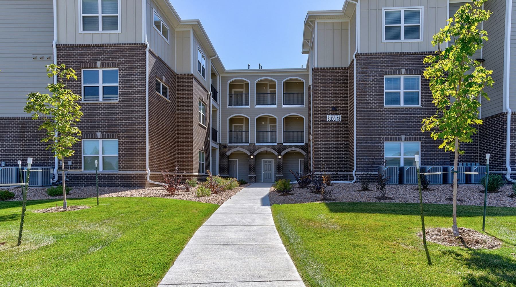 a large building with trees and a sidewalk